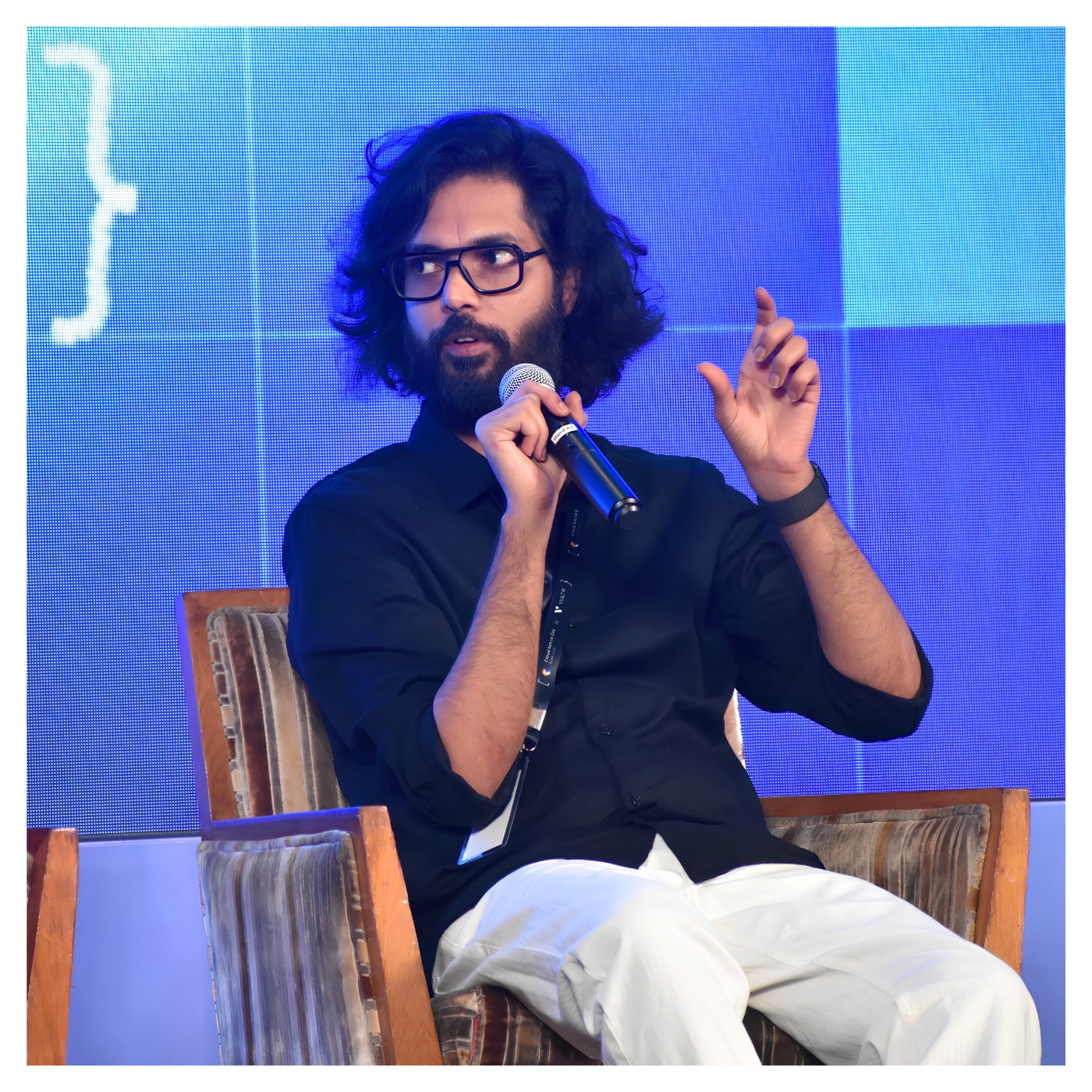 Priyank Upadhyay on stage, mid-sentence, microphone in hand.